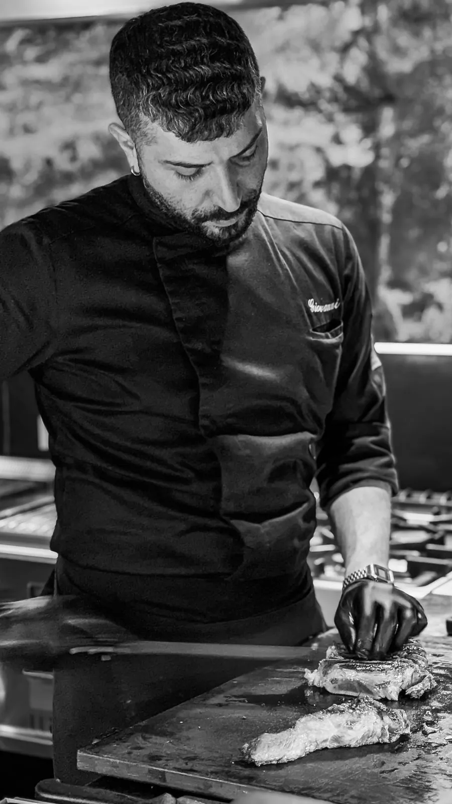 Lo chef al lavoro alla piastra, in bianco e nero